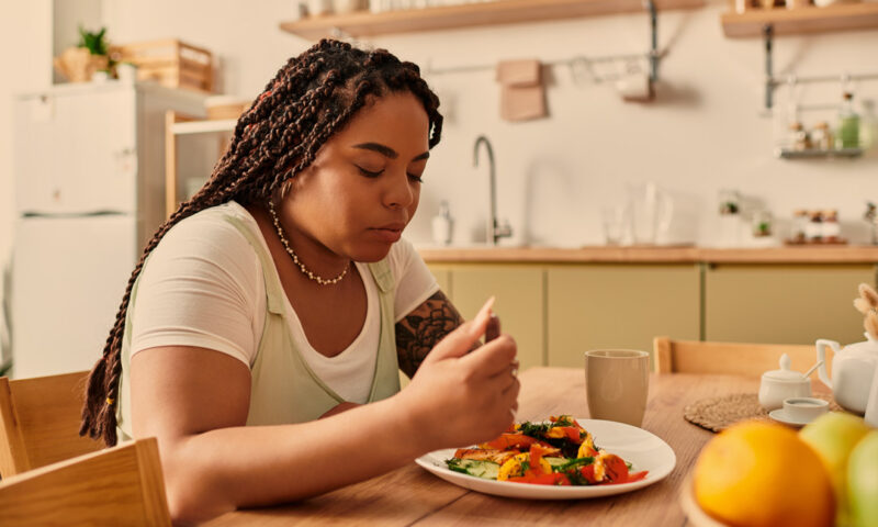 frau sitzt an tisch uns isst nachdenklich ihr essen