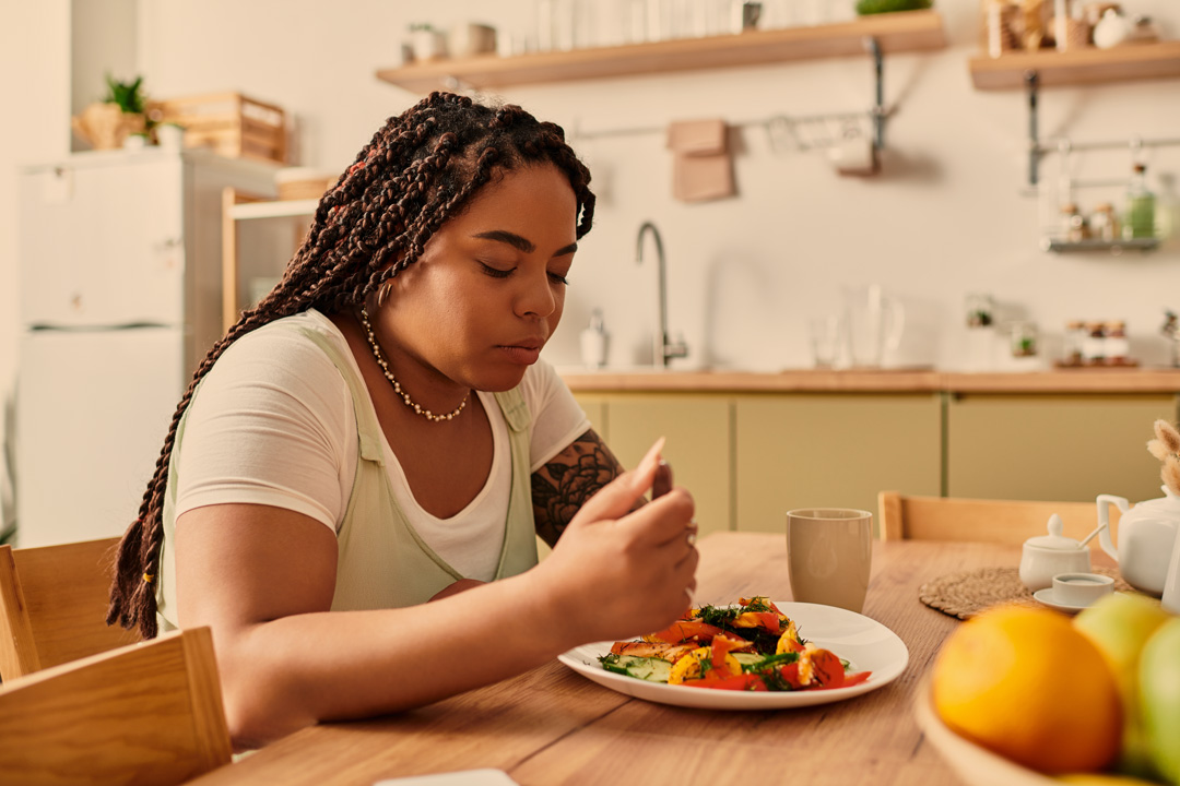 frau sitzt an tisch uns isst nachdenklich ihr essen