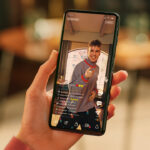 person haelt handy in der hand und sieht sich einen livestream an