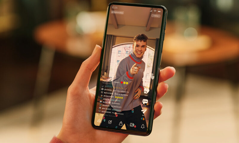 person haelt handy in der hand und sieht sich einen livestream an